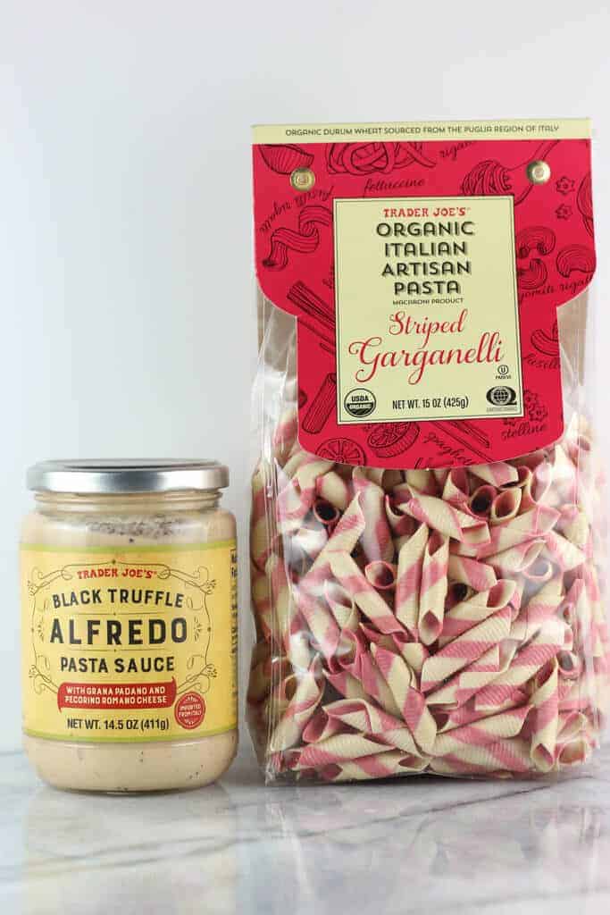 An unopened jar of Trader Joe's Black Truffle Alfredo Pasta Sauce and a bag of unopened Organic Italian Garganelli