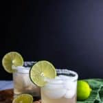 Two finished Spicy Jalapeno Limeade Margarita garnished with limes