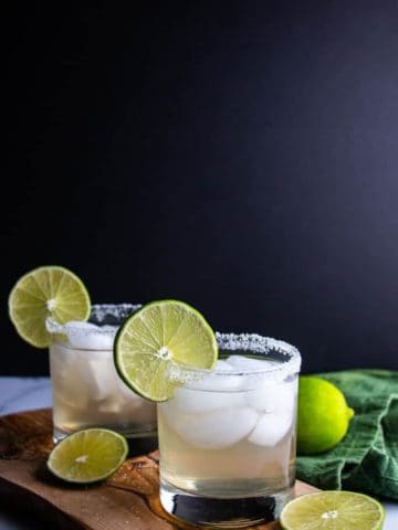 Two finished Spicy Jalapeno Limeade Margarita garnished with limes