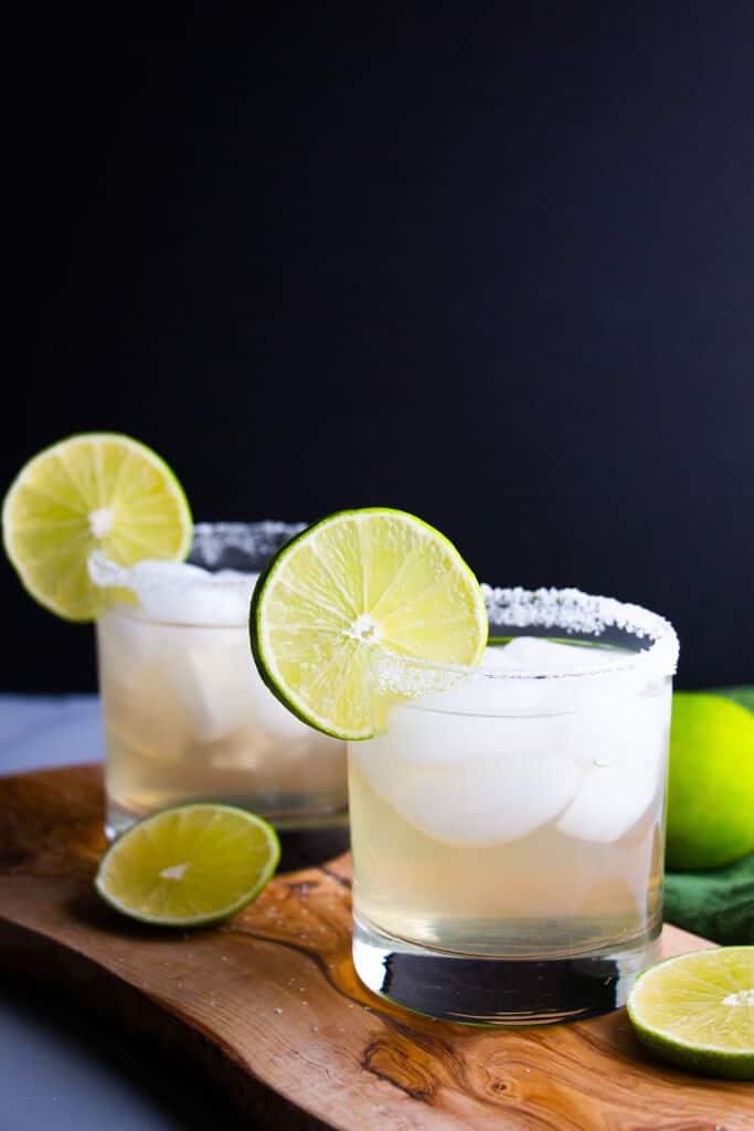 A closer look at two finished spicy jalapeno limede margaritas that have been garnished with lime wheels