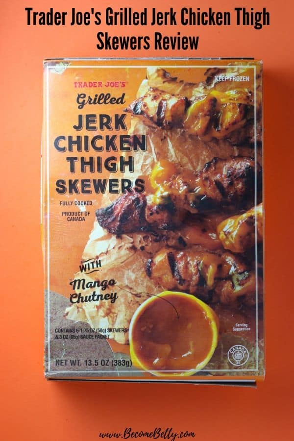 An unopened box of Trader Joe's Grilled Jerk Chicken Thigh Skewers on an orange background