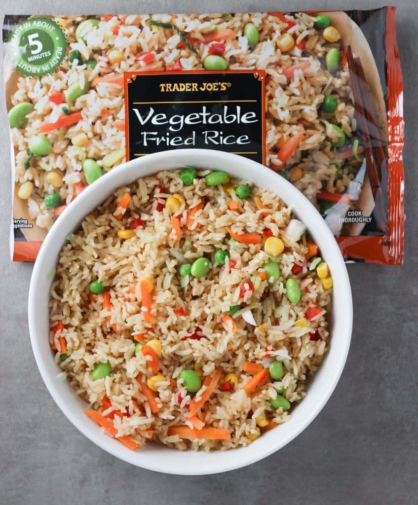 Trader Joe's Vegetable Fried Rice heated through in a white bowl next to the original bag.