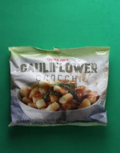 An unopened bag of Trader Joe's Cauliflower Gnocchi bag on a green background