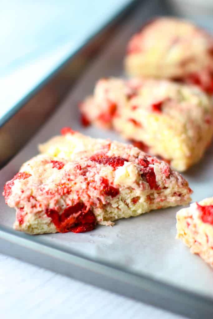 Strawberry scones cut and placed on a cookie sheet and on the side showing the texture of the dough
