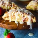 Strawberry scone with glaze on a wooden lazy susan with glaze dripping off the side