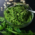 A finished pesto with parsley and almonds surrounding it.
