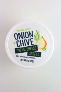 An unopened container of Trader Joe's Onion and Chive Cream Cheese Spread on a white background