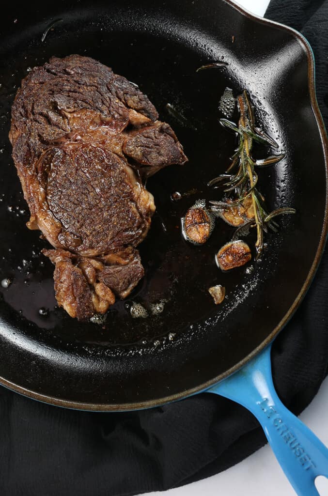 A fully cooked Ribeye Steak in a cast iron skillet 