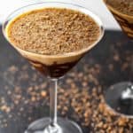 A close up of two chocolate martinis with chocolate shavings on the black surface