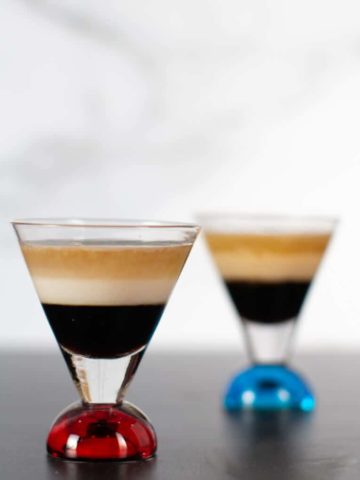 Two finished B 52 Cocktails. The shot glass that has a red bottom is the non diary, the shot glass with a blue bottom has the Irish Cream Liqueur