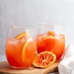 Two finished greyhound cocktails with slices of grapefruit all around