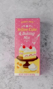 An unopened box of Trader Joe's Yellow Cake and Baking Mix on a grey surface.