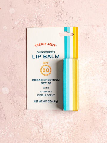 A small tube of lip balm on a pink background