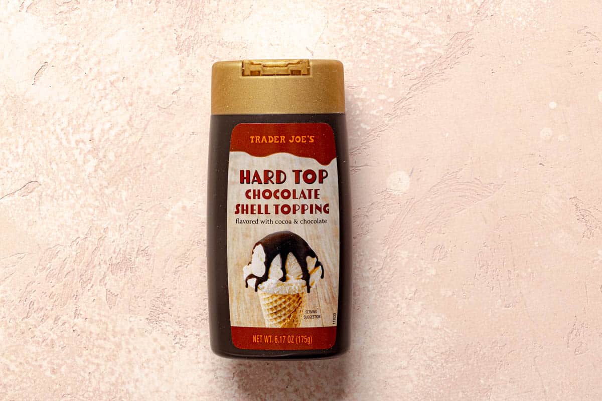 Trader Joe's Hard Top Chocolate Shell Topping unopened on a pink surface.