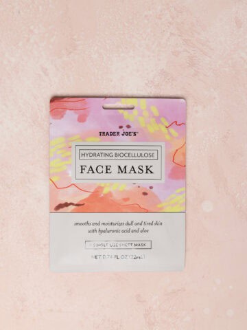 An unopened Trader Joe's Hydrating Biocellulose Face Mask on a pink surface.