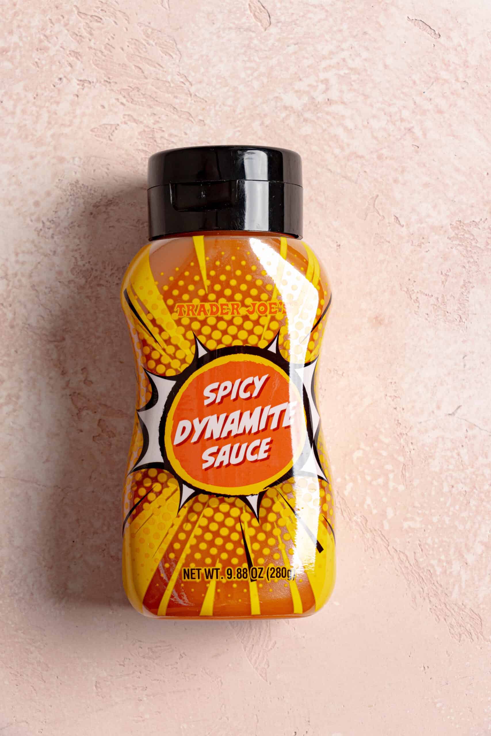 Trader Joe's Spicy Dynamite Sauce on a pink surface.