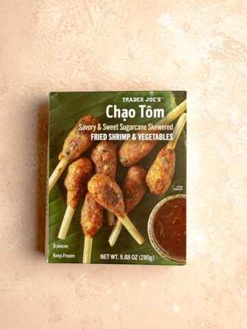 An unopened package of Trader Joe's Chao Tom on a pink surface.