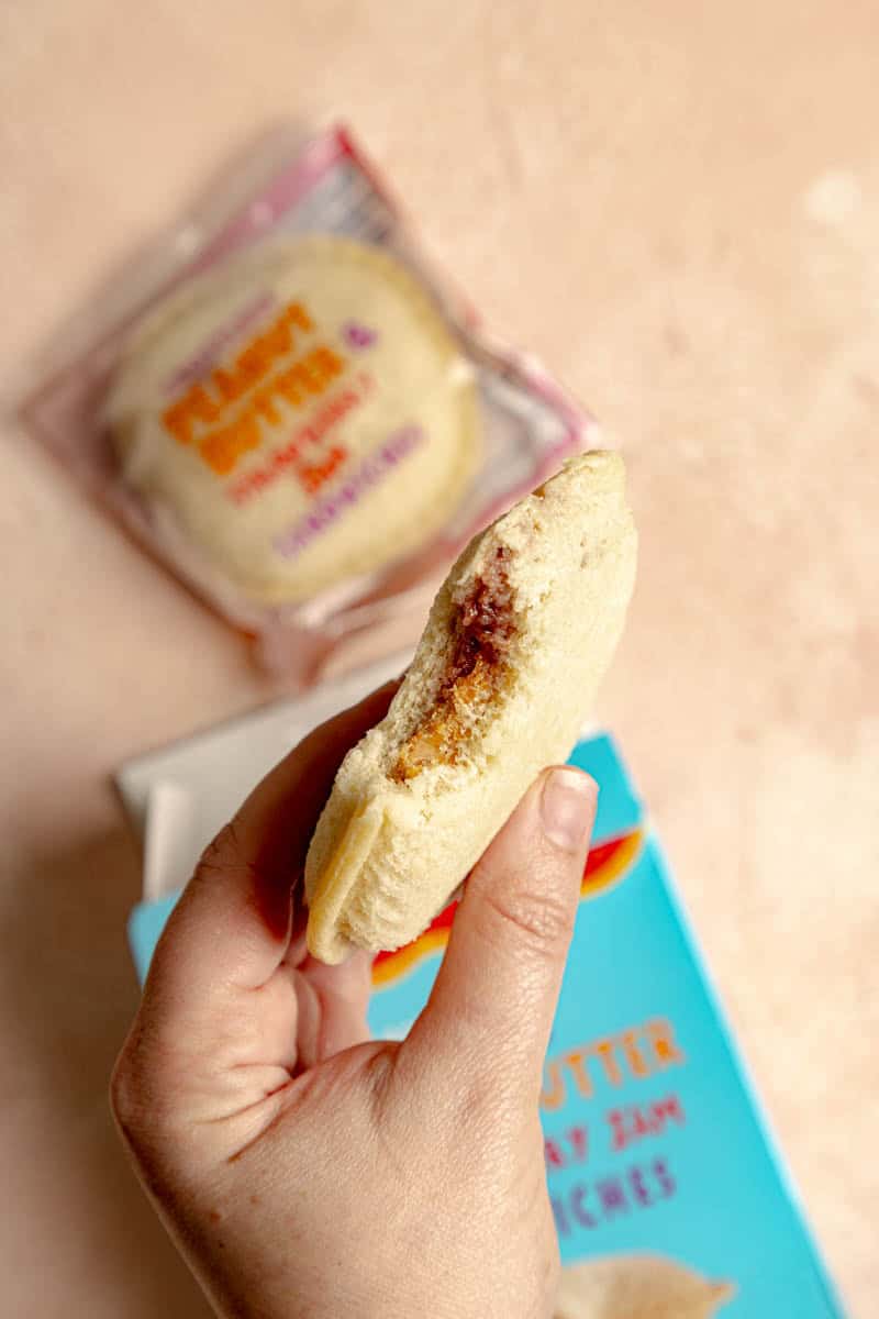 An opened box of Trader Joe's Crustless Peanut Butter and Strawberry Jam Sandwiches showing one open and bitten into.