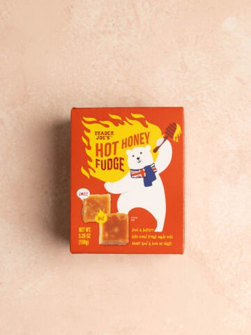 An unopened box of Trader Joe's Hot Honey Fudge on a pink surface.