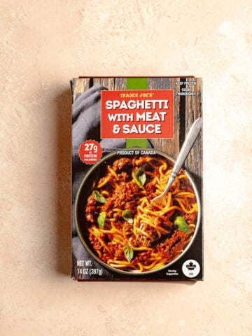 A box of Trader Joe's Spaghetti with Meat and Sauce on a pink surface.