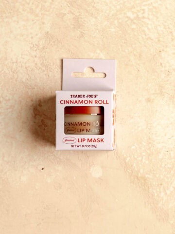 Trader Joe's Cinnamon Roll Flavored Lip Mask unopened on a pink surface.