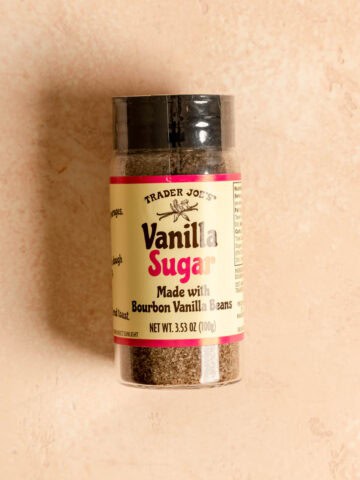 An unopened jar of Trader Joe's Vanilla Sugar on a pink surface.