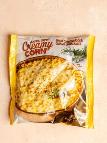 Trader Joe's Creamy Corn unopened on a pink surface.