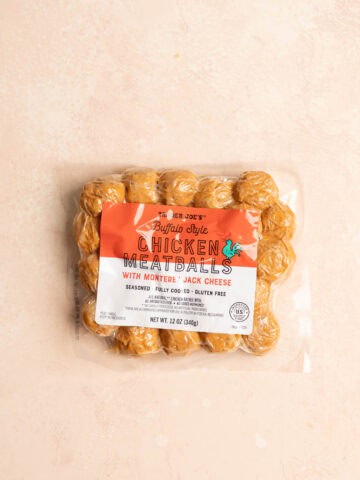 An unopened package of Trader Joe's Buffalo Style Chicken Meatballs on a pink surface.