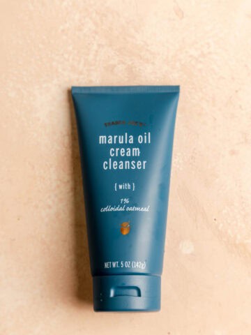 An unopened package of Trader Joe's Marula Oil Cream Cleanser on a pink surface.