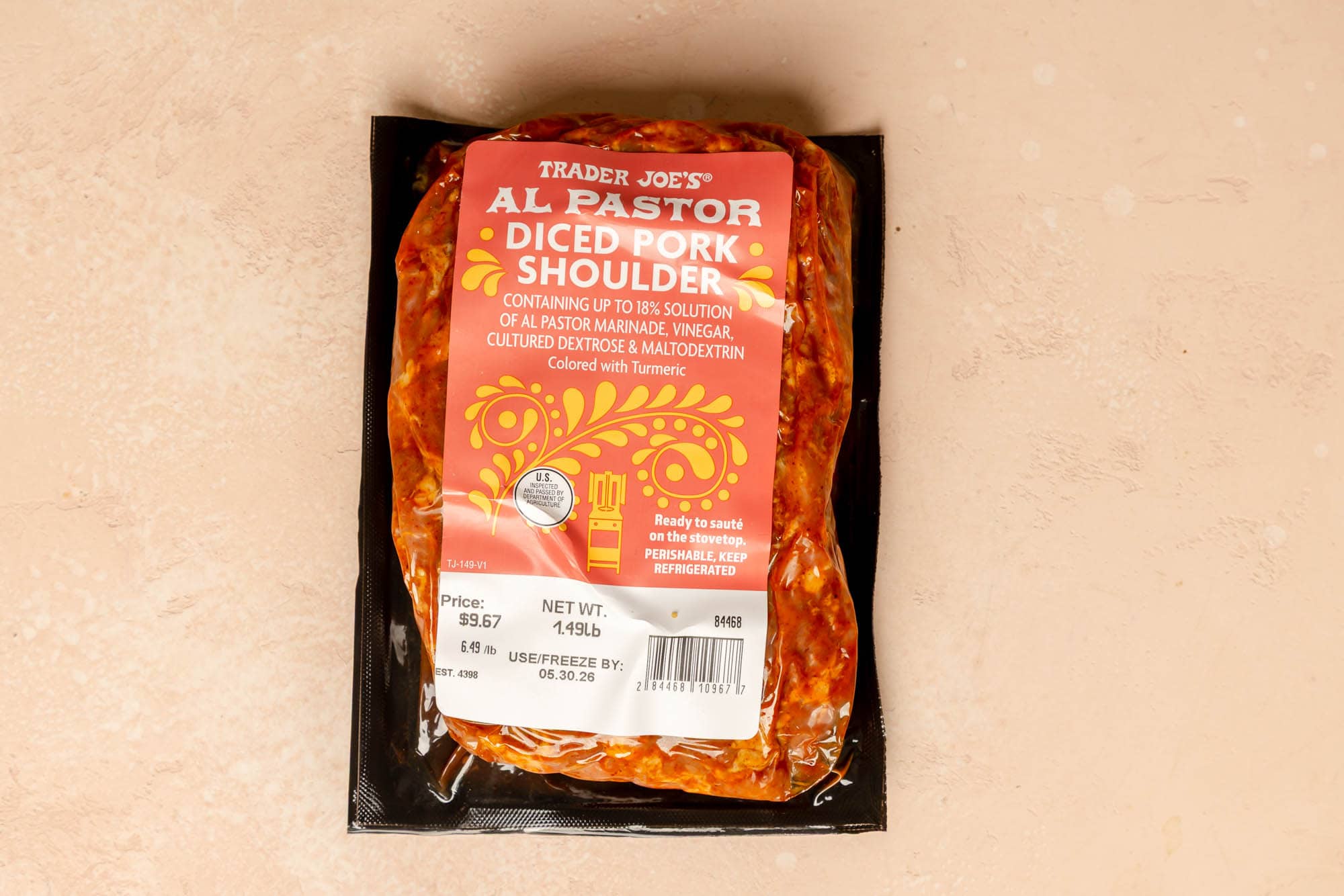 Trader Joe's Al Pastor Diced Pork Shoulder unopened on a pink surface.