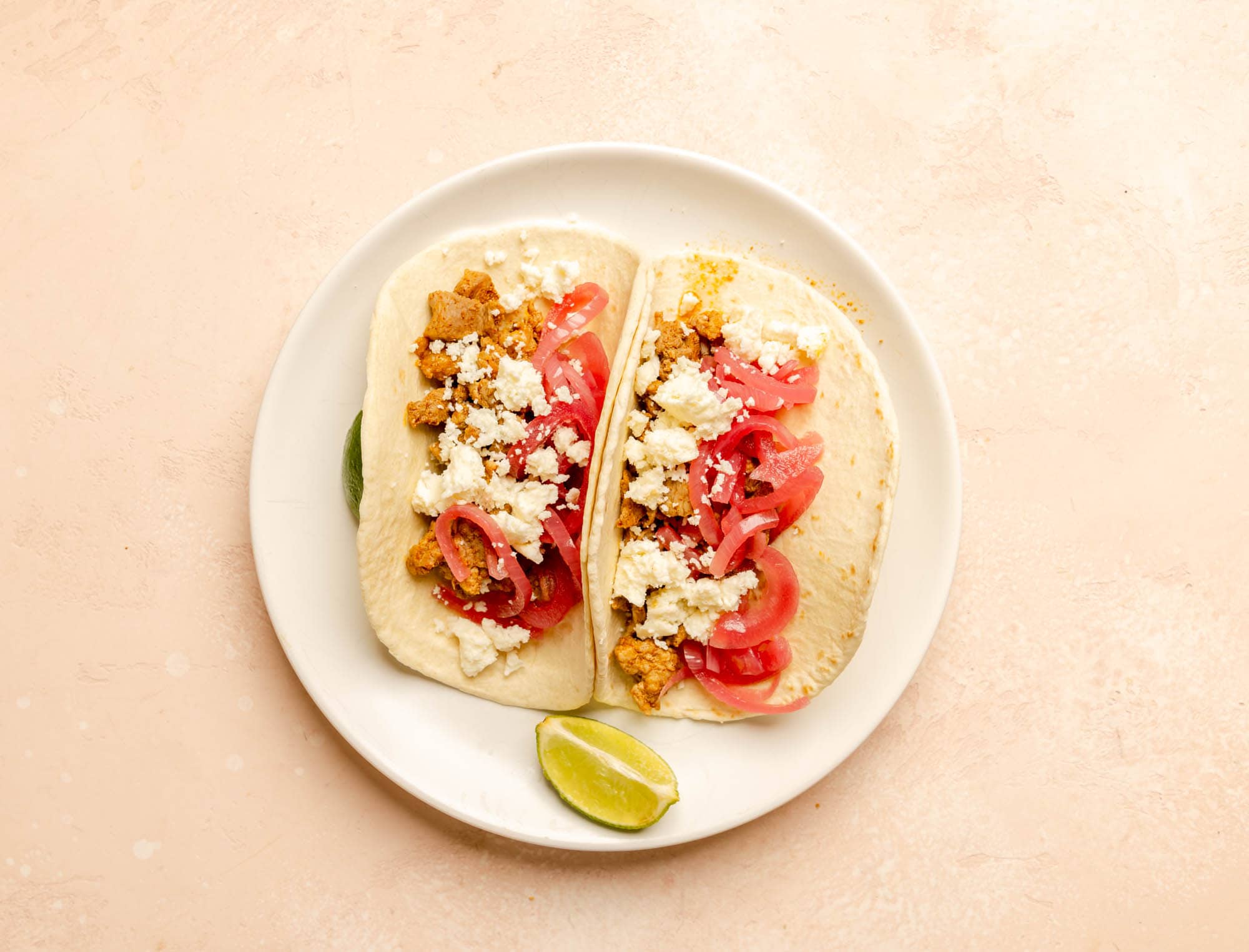 Two tacos with Trader Joe's Al Pasto, Pickled Red Onions, and Queso Fresco.