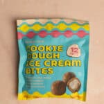 An unopened package of Trader Joe's Cookie Dough Ice Cream Bites on a pink surface.