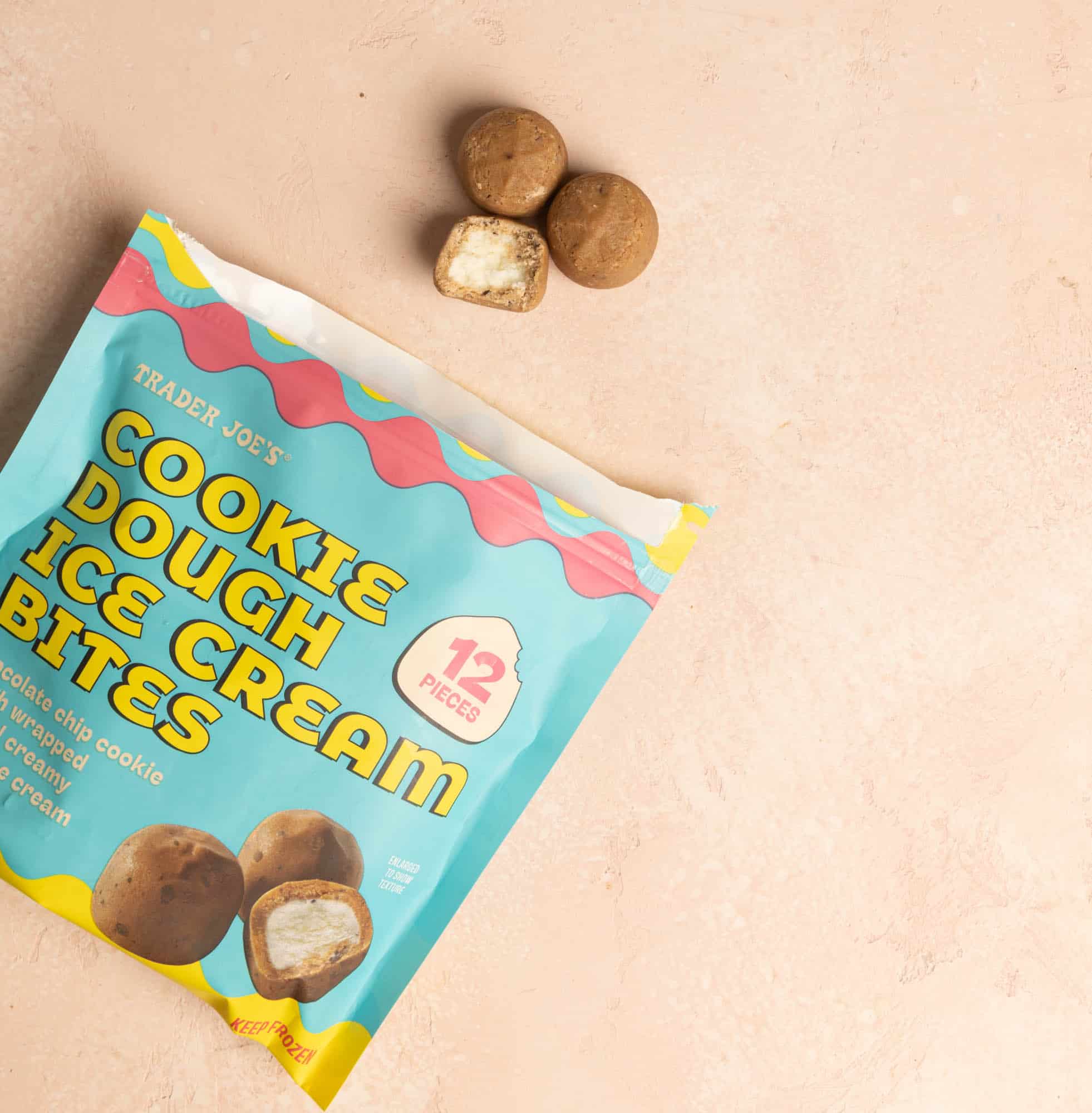 Trader Joe's Cookie Dough Ice Cream Bites opened and three out of the bag with one showing a bite in it.