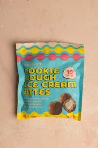 An unopened package of Trader Joe's Cookie Dough Ice Cream Bites on a pink surface.
