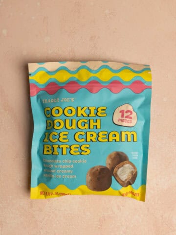 An unopened package of Trader Joe's Cookie Dough Ice Cream Bites on a pink surface.