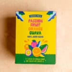 An unopened box of Trader Joe's Passion Fruit Orange Guava Juice on a pink surface.