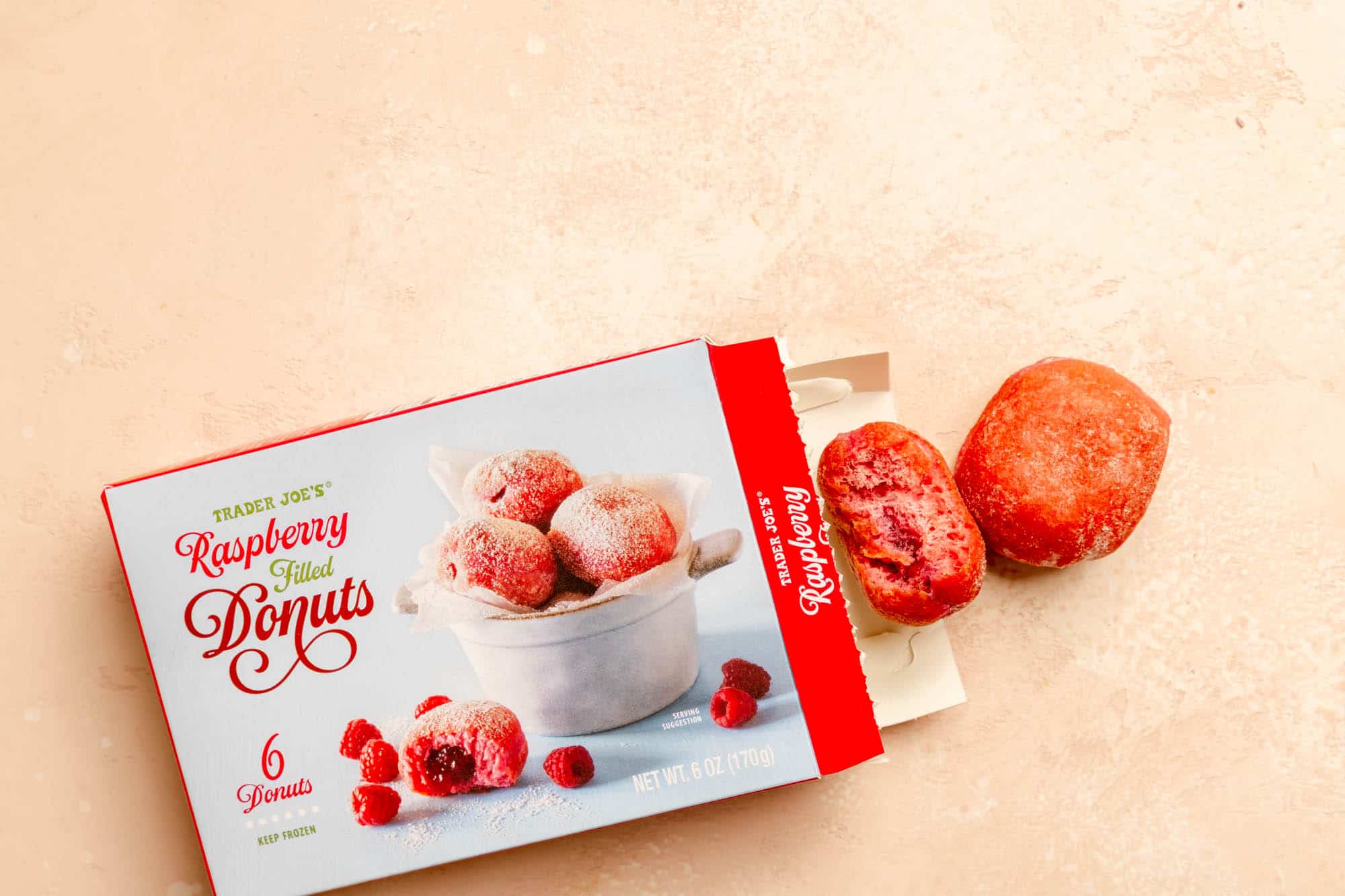 Trader Joe's Raspberry Filled Donuts with the box open showing two donuts with one bitten into.